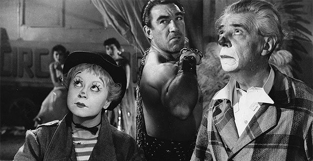 La strada - Giulietta Masina nei panni di Gelsomina indossa il cappotto largo e la tromba con la sua espressione clownesca